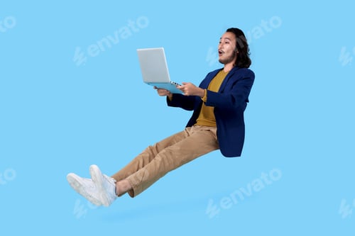 Preview: asian businessman hand holding computer laptop floating in mid-air isolated on blue background.