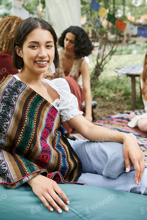 Preview: stylish and smiling woman looking at camera near blurred multiethnic women in retreat center