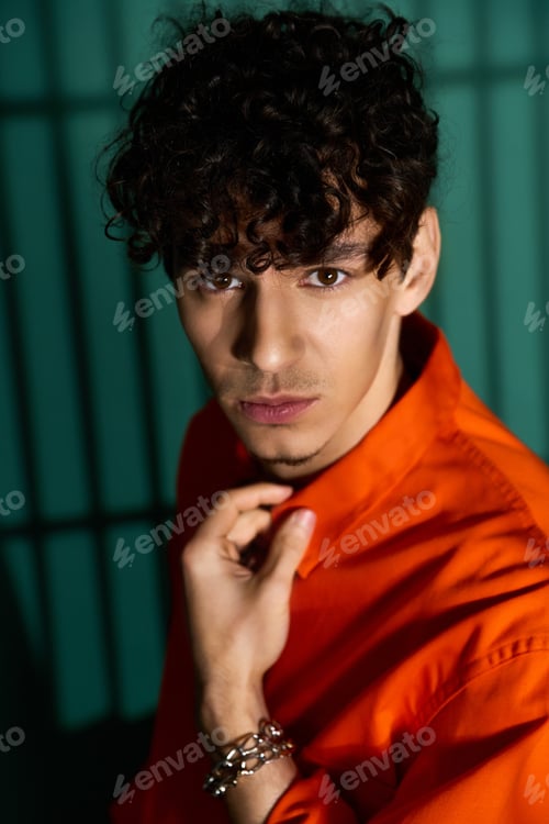 Preview: Stylish curly man poses confidently in trendy outfit surrounded by studio lights