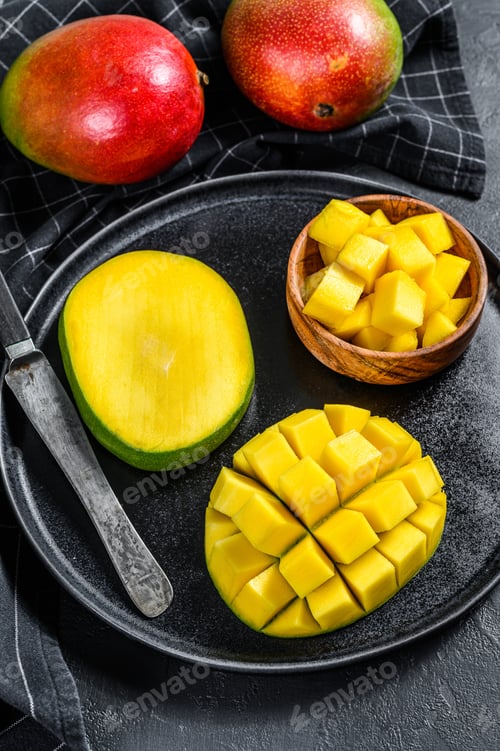 Preview: A ripe mango. Cut into cubes tropical fruit. Black background. Top view