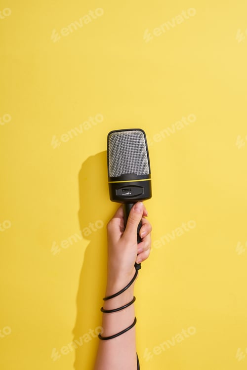 Preview: cropped view of woman holding microphone on yellow background