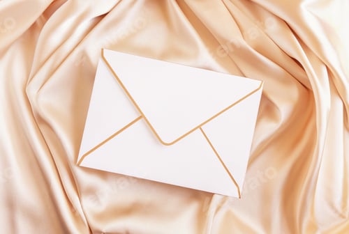 Preview: Blank envelope on beige silky fabric drapery top view, greeting or wedding mockup