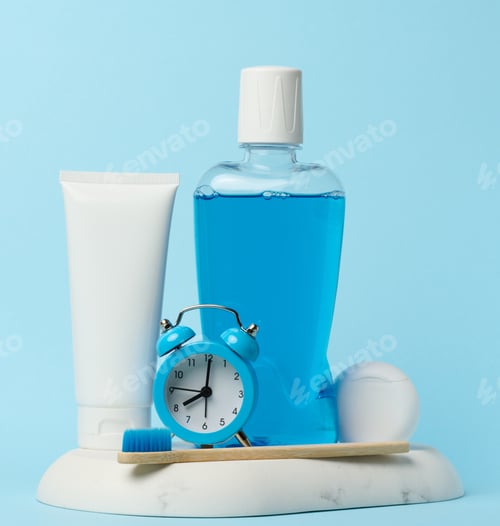 Preview: Mouthwash and toothpaste tube, alarm clock on blue background, oral hygiene