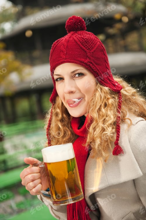 Preview: Germany, Bavaria, English Garden, Woman in beer garden holding beer mug, licking her lips, portrait