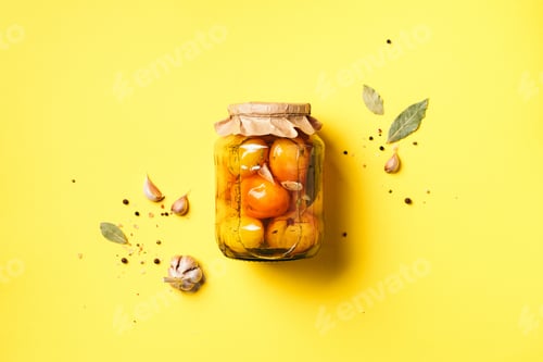 Preview: Pickled tomatoes in jar on yellow background. Top view. Flat lay. Copy space. Canned and preserved