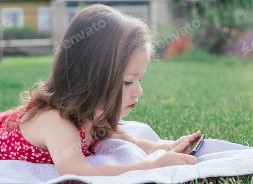 Preview: Girl Lying on Blanket Using Mobile Phone Outdoors
