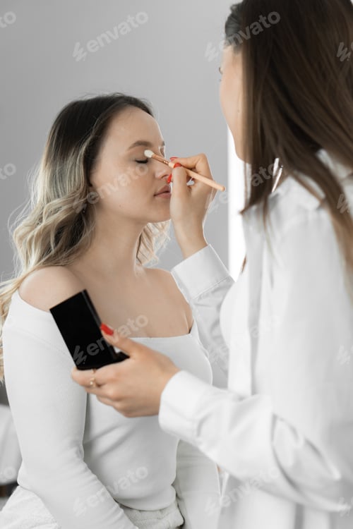 Preview: Young woman sits in comfortable chair beauty salon like professional makeup artist applies makeup to
