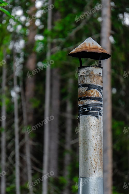 Preview: Vertical shot of a rustic smokestack in the forest on blurred background