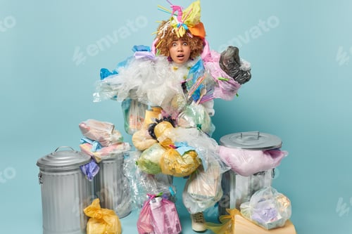 Preview: Studio shot of curly haired woman collects plastic rubbish tries to clean environment from