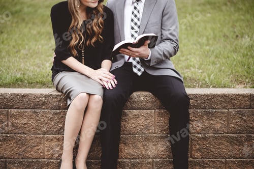 Preview: Midsection of a couple sitting on blocks and lovingly reading a book