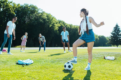 Preview: happy teenage multiethnic friends playing with soccer ball in park