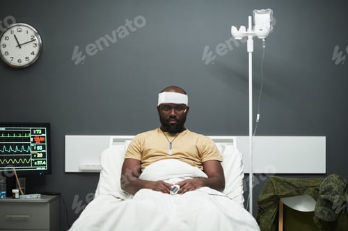 Preview: Young African American soldier sitting in bed and looking at camera