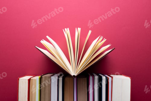 Preview: Books and notebooks in row with opened notebook on top and copy space on red background