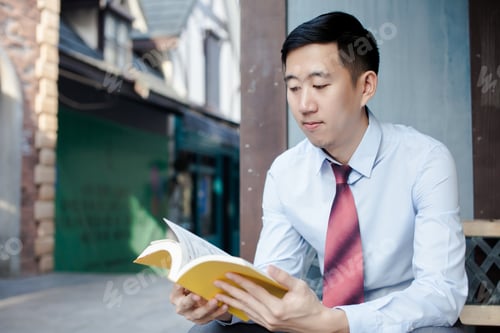 Preview: Asian Man Reading a Book Sitting on Bench