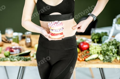 Preview: Sports woman with donuts and healthy food