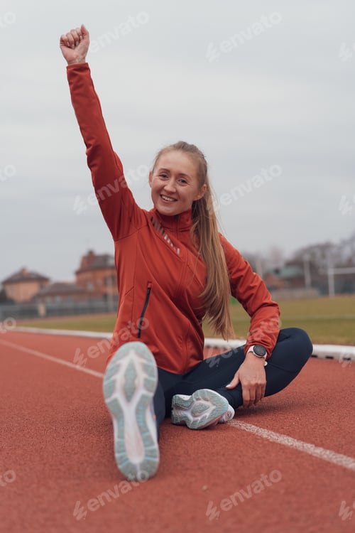 Preview: Portrait of young fitness woman running at a track and field stadium