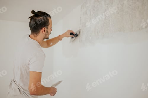Preview: Man Smoothing Plaster on Wall During Home Renovation