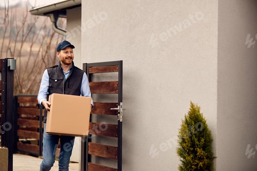 Preview: Smiling delivery man carrying cardboard box and delivering package to customer's home.
