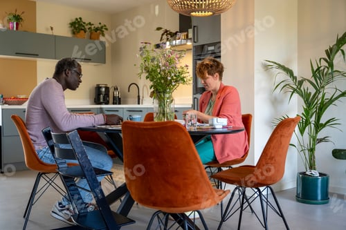 Preview: Mixed race parents sitting at the kitchen table discussing life