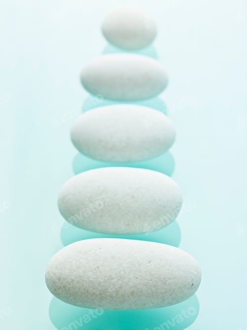 Preview: Smooth white pebbles of uniform size and colour displayed on a blue reflective glass background.