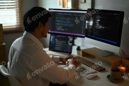 Preview: Skilled male programmer working with coded data on computer screen in dark room
