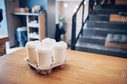 Preview: High angle shot of a cardboard take out tray with four coffee cups with lids