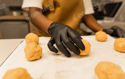 Preview: African woman preparing dough balls on baking sheet
