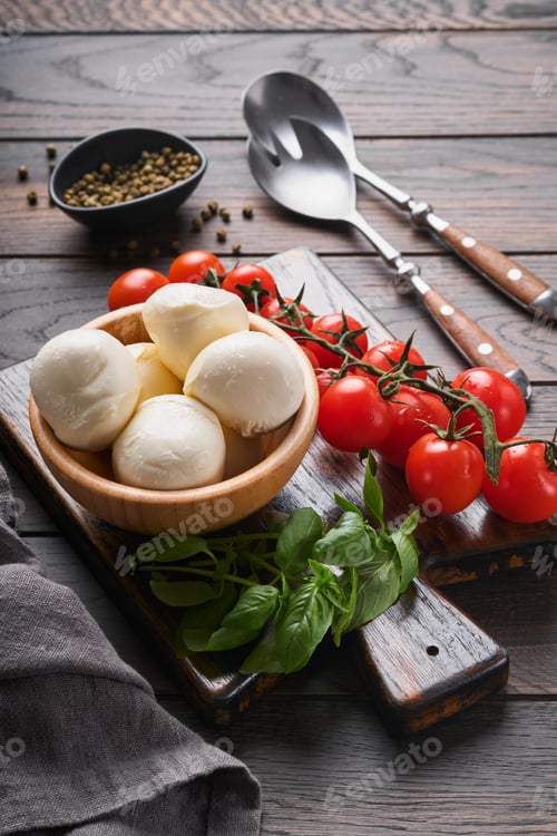 Preview: Caprese salad, ingredients for cooking. Cutting wooden board with traditional caprese preparation i