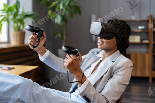 Preview: Excited afro woman wear vr glasses hold joystick experience of virtual reality headset for business