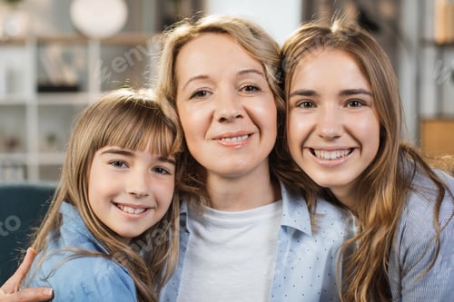 Preview: Portrait of mother hugging two little kids. Joyful affectionate mom cuddling sweet sibling daughters