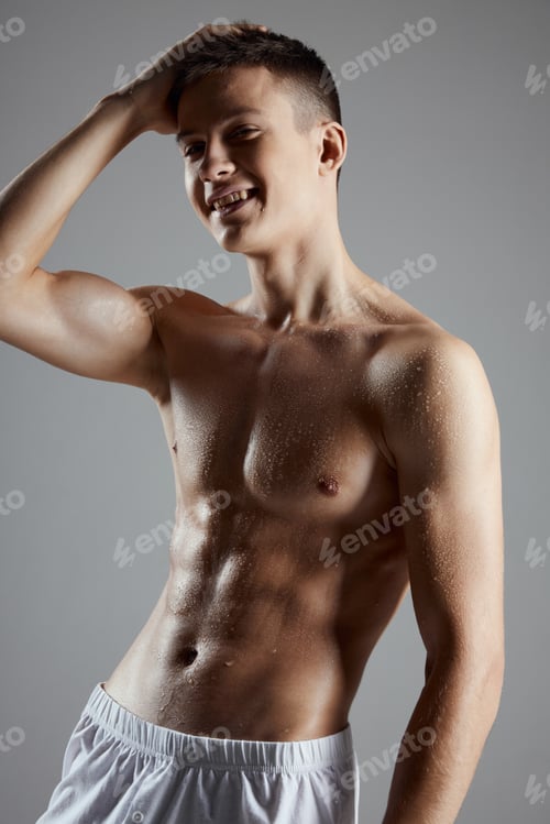 Preview: bodybuilder with a pumped up torso in white shorts on a gray background cropped view