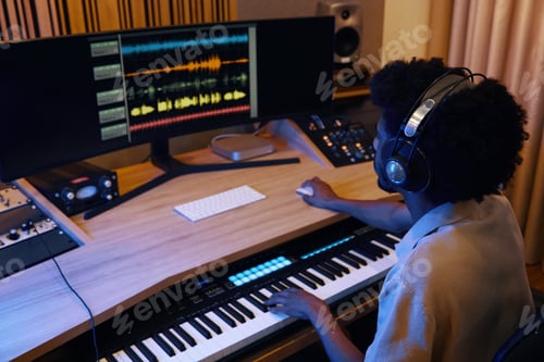 Preview: Person Composing Music at Studio Desk with Headphones