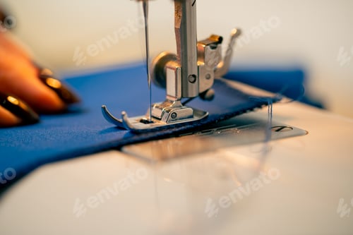 Preview: close-up in a sewing workshop on a machine the seamstress master makes cut on a blue fabric