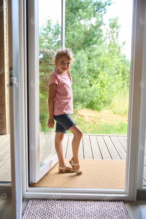 Preview: Pretty smiling schoolgirl standing and posing on big wooden porch