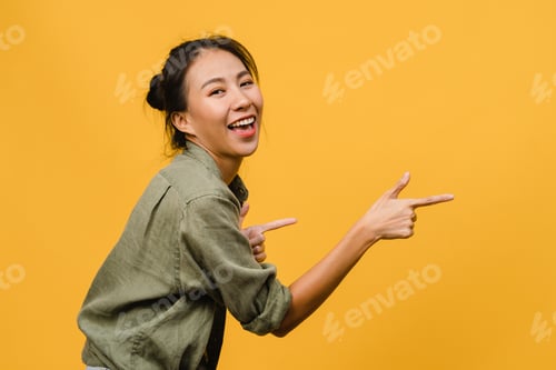 Preview: Portrait of young Asian lady smiling with cheerful expression stand isolated on yellow background.