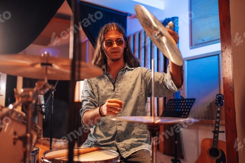 Preview: Portrait of drummer sitting at recording studio and adjusting cymbal.