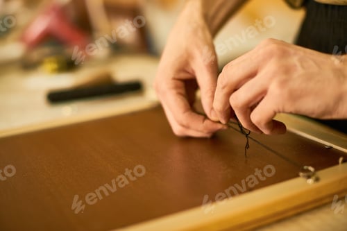 Preview: Man Fastening Wire on Wooden Frame with Hands Visible