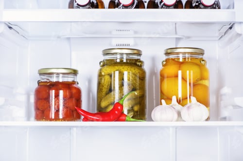 Preview: preserved vegetables in glass jars and ripe chili peppers in fridge