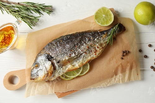 Preview: Baking paper with Dorado on garnished wooden background, top view