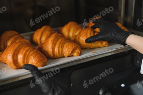 Preview: Baker taking freshly baked croissants out of oven