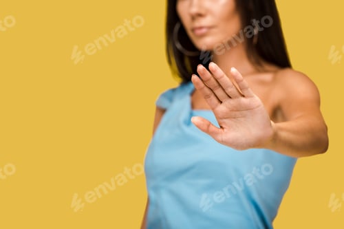 Preview: cropped view of woman showing stop sign isolated on orange