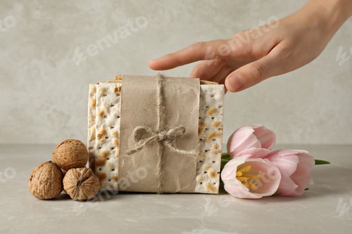 Preview: Matzo, hand, flowers and nuts on beige background