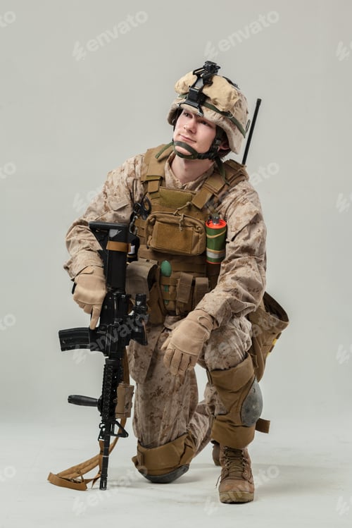 Preview: Militarily dressed soldier kneeling with weapon on display in indoor setting