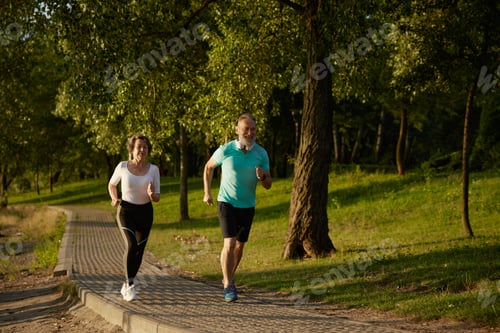 Preview: Lovely joyful retirees couple jogging outside in city park