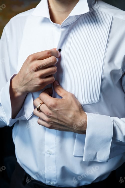 Preview: Man Buttons Tuxedo Shirt Before Formal Event