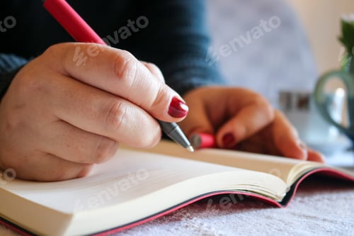 Hands Writing in a Notebook with Red Pen