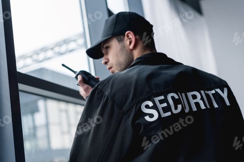 Preview: rear view of guard in uniform talking on walkie-talkie