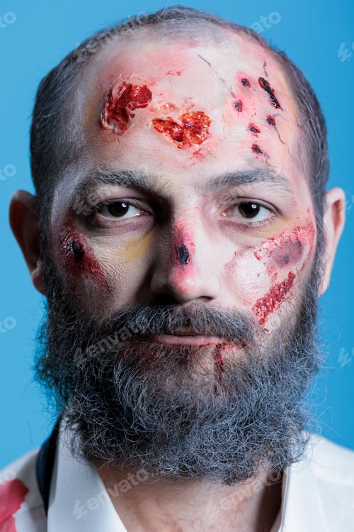 Preview: Portrait of wounded actor dressed as horror movie zombie, studio background