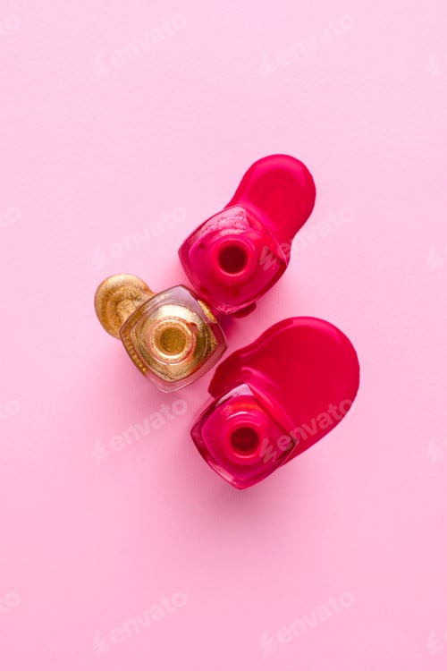 Preview: Cosmetic pink and gold nail polishes on a pink background