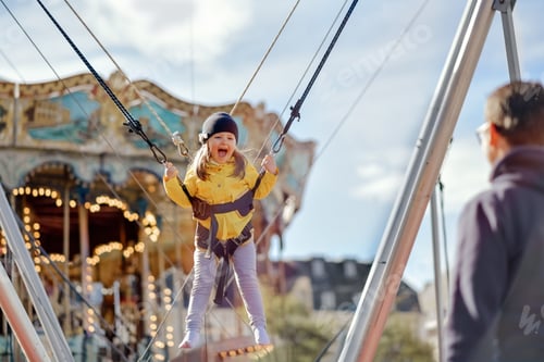 Preview: A smilling girl jumping on a trampoline with insurance and looks at a father